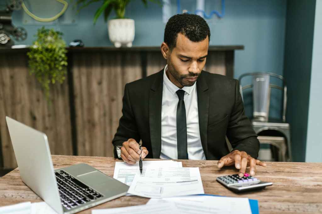Man in a suit reviewing financial documents at a desk.